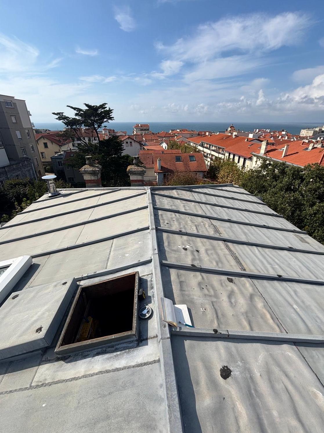 Vue aérienne d'une toiture en zinc à tasseaux, réalisée par l'entreprise SOS Couvreur 40 & 64 à Dax. Travaux de zinguerie d'art et étanchéité de lucarne, expertise certifiée Meilleur Ouvrier de France.